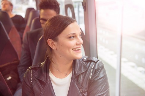 Vrouw zit in de bus en kijkt uit het raam.