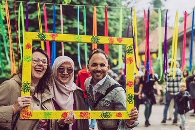 festivalbezoekers kijken door een grote, gele fotolijst voor kleurige linten